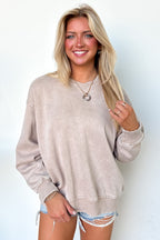 Woman wearing a beige sweater and denim shorts against a light background