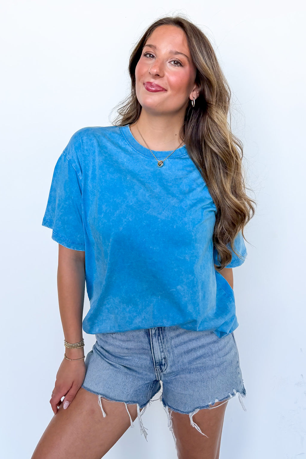 Woman wearing a blue t-shirt and denim shorts against a white background