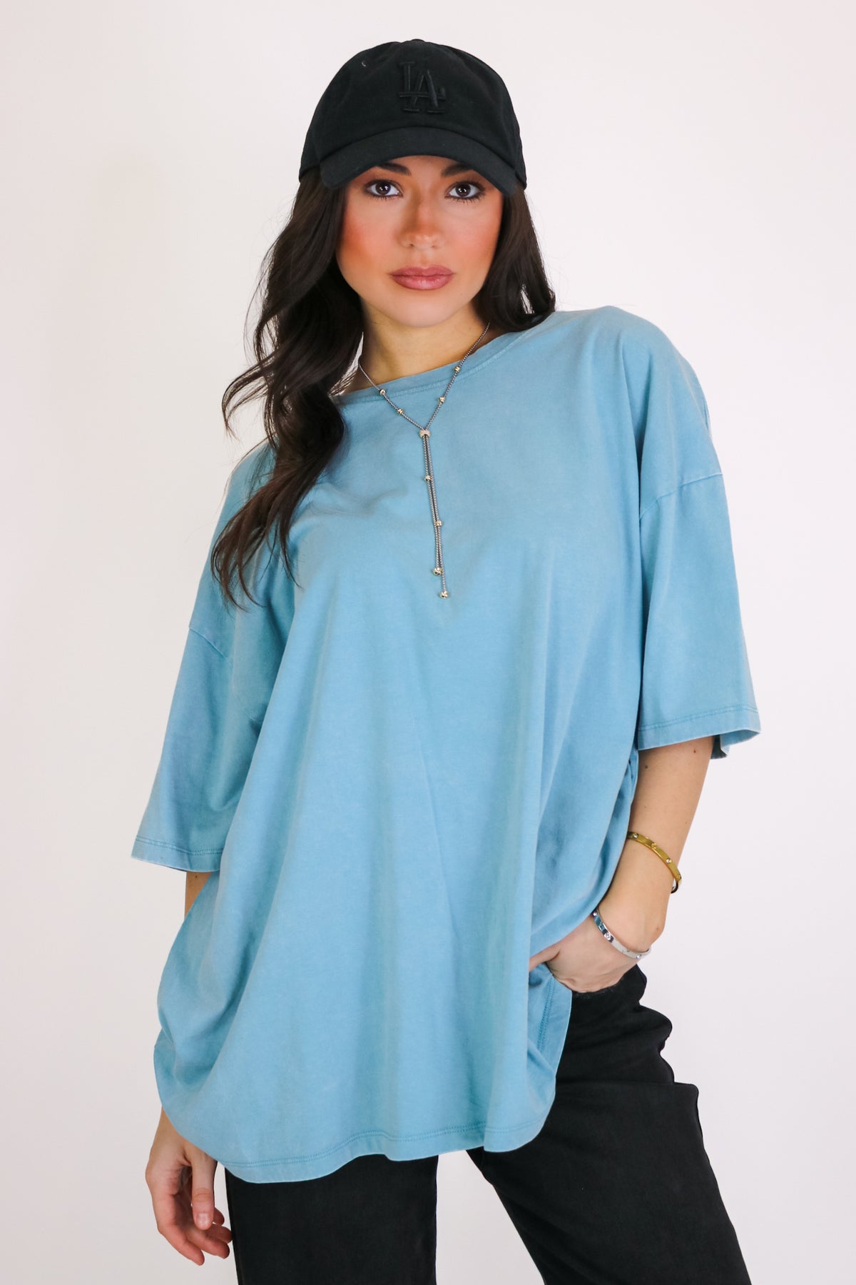 Weekend Awaits Mineral Wash Oversized Top in Turquoise with black pants and a ball cap, front view